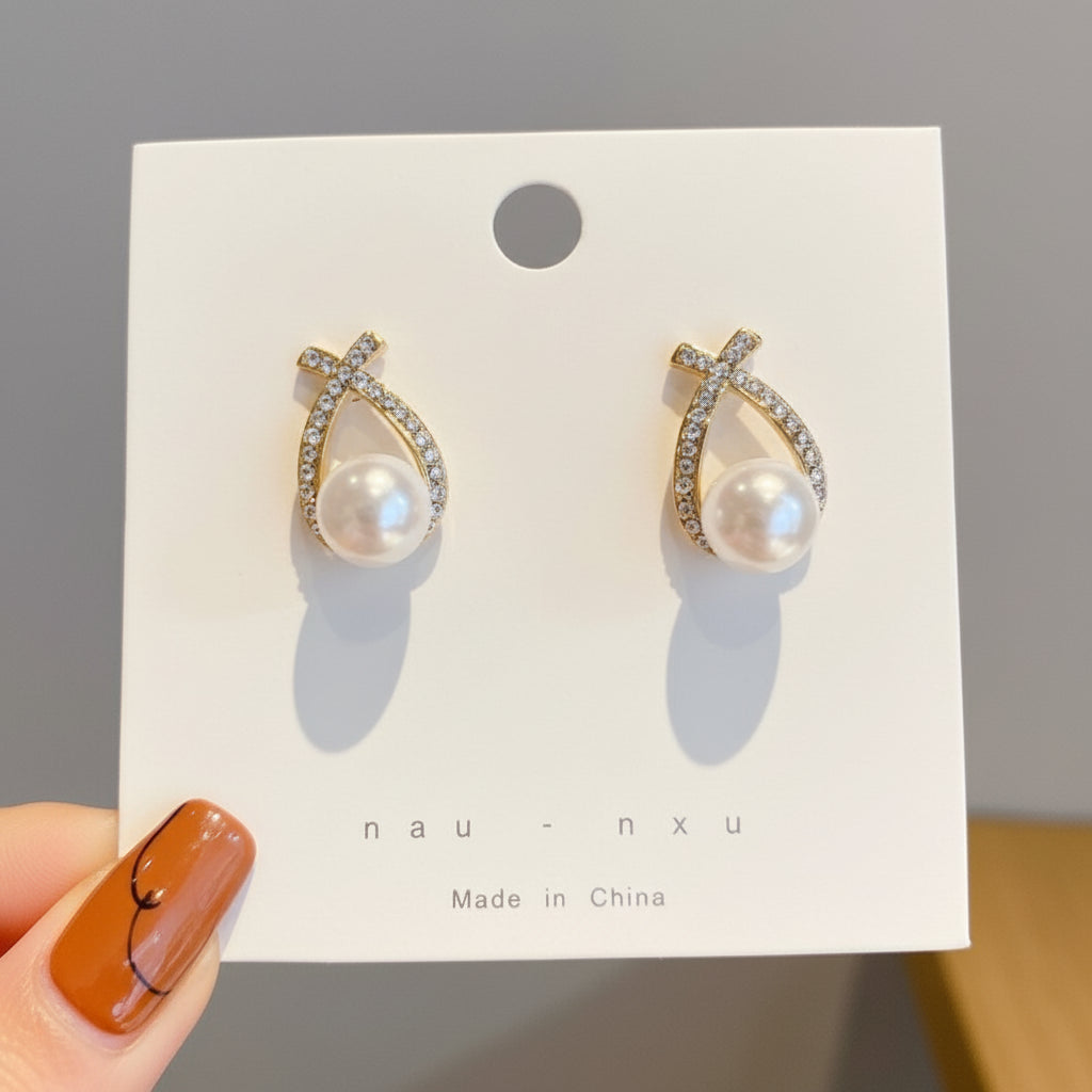 Pair of earrings on a white card with 'Made in China' text, held by a hand.