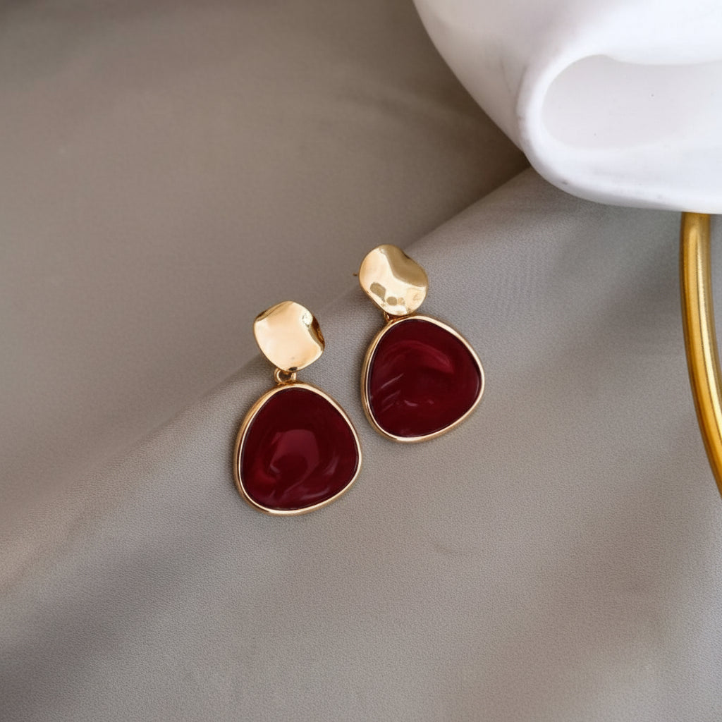 Red teardrop earrings with gold accents on a white background