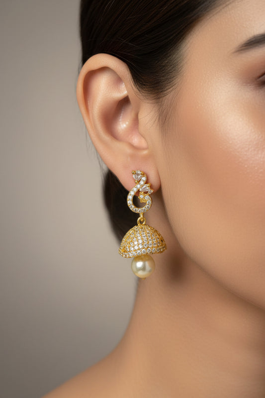 Gold earrings on a white card held by a hand against a dark background