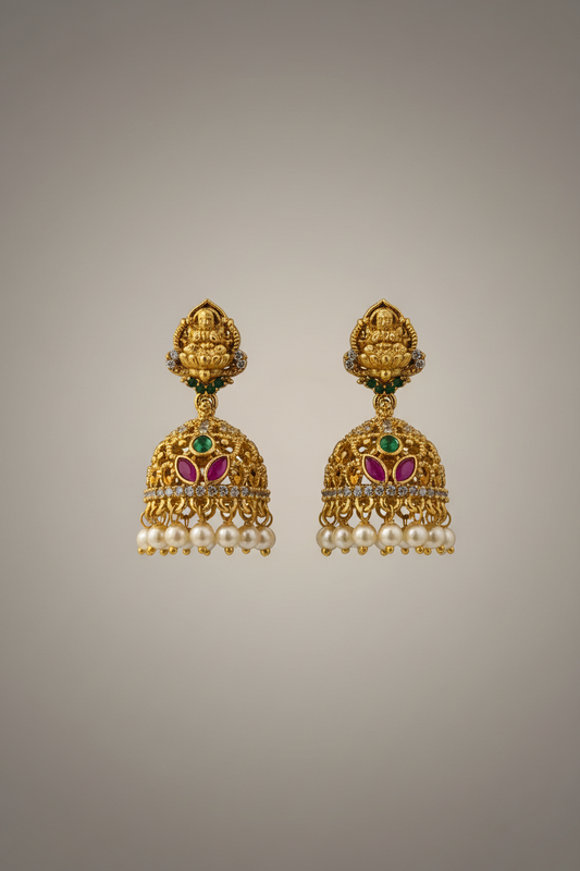Gold earrings with pearls and gemstones on a gray background
