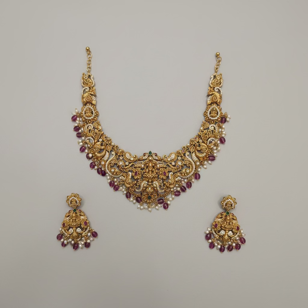 Ornate gold necklace and earrings set on a black square background