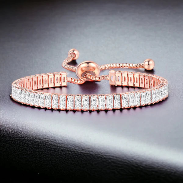Rose gold bracelet with clear gemstones on a dark gray background