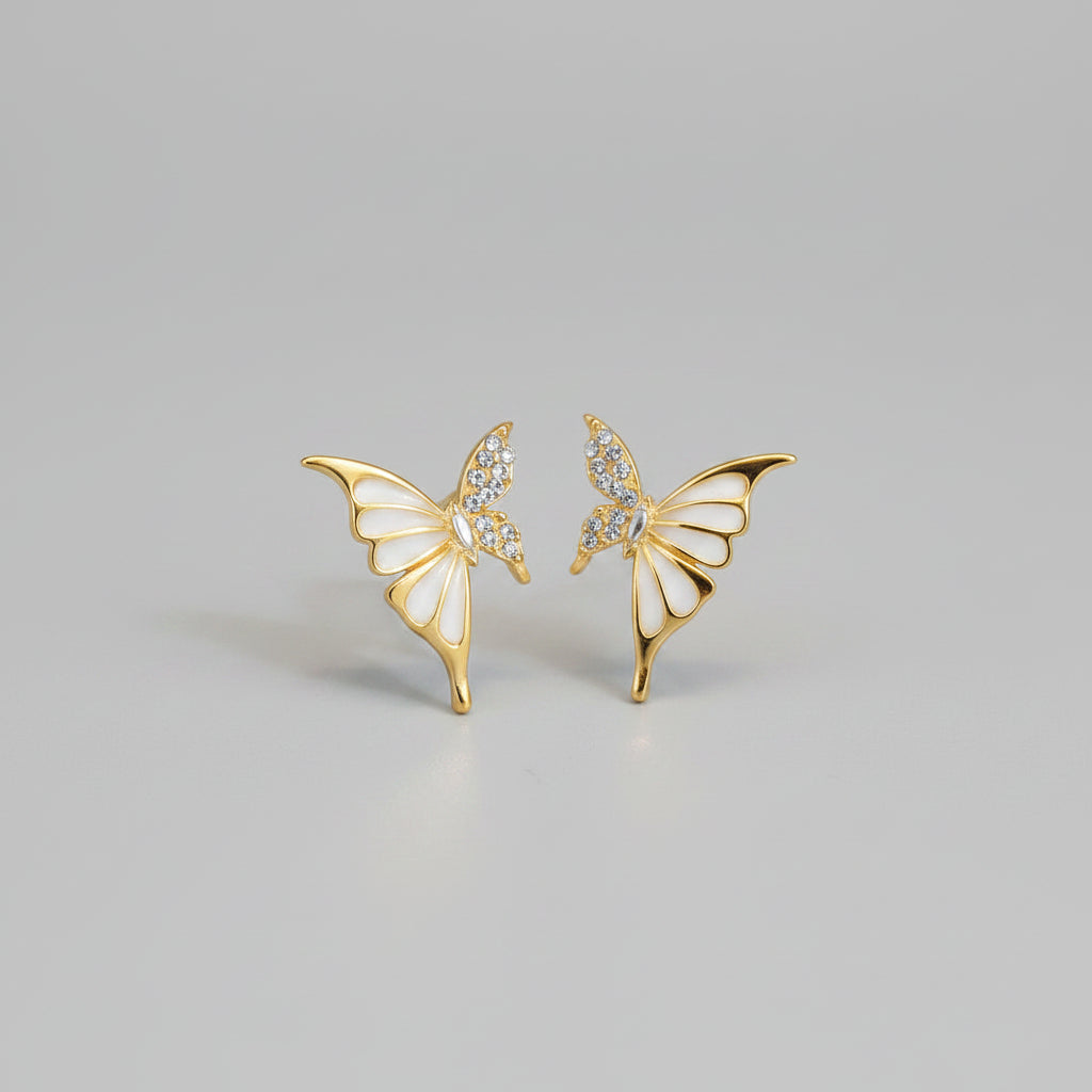 Gold butterfly earrings with gemstones on a soft surface