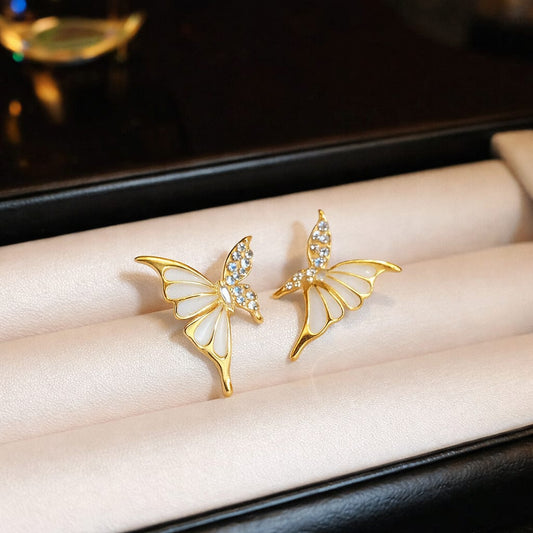 Gold butterfly earrings with gemstones on a soft surface