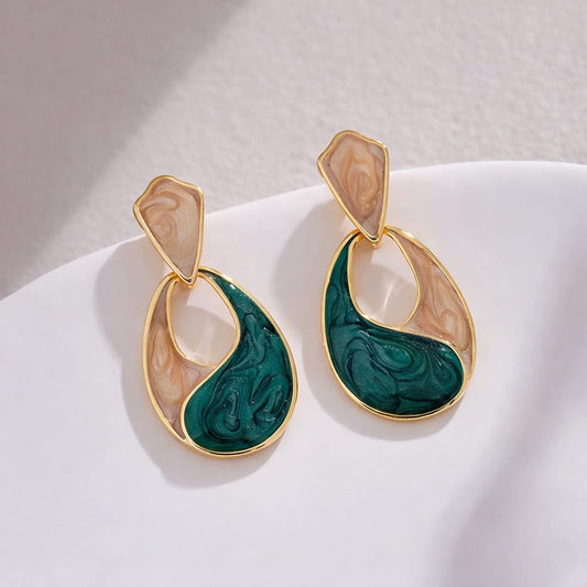 Pair of earrings with green and beige marbled design on a white surface