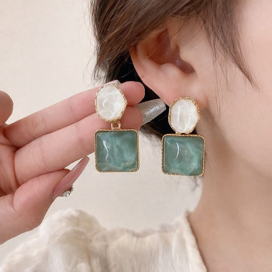 Close-up of a person wearing a pair of earrings with a hand adjusting them.