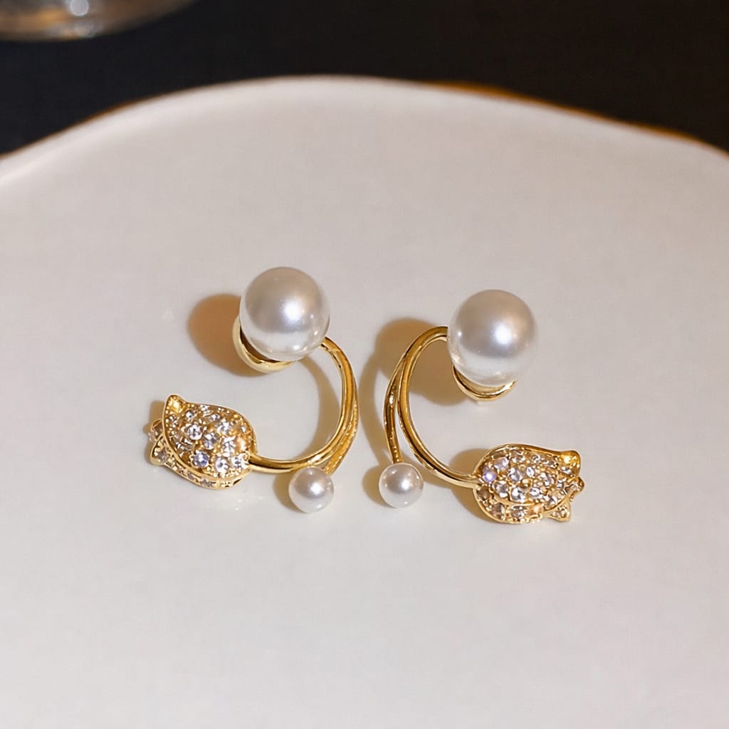 Gold earrings with pearls on a white plate