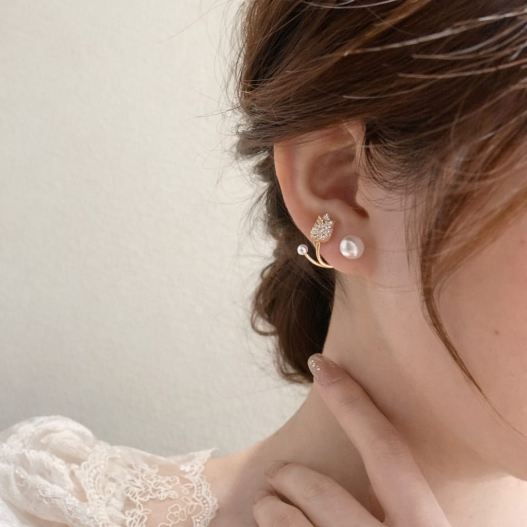 Close-up of an ear wearing a pearl earring with a delicate background