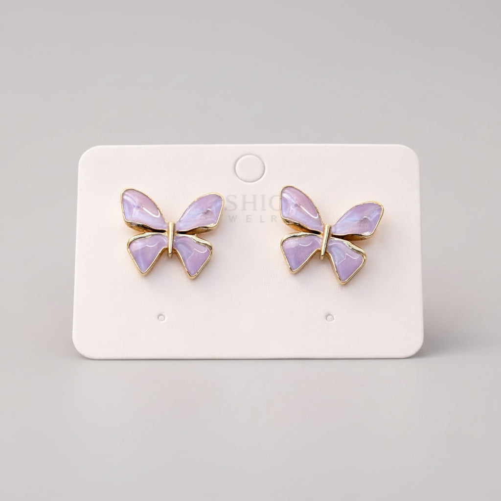 Butterfly-shaped earrings on a white card with a soft, blurred background
