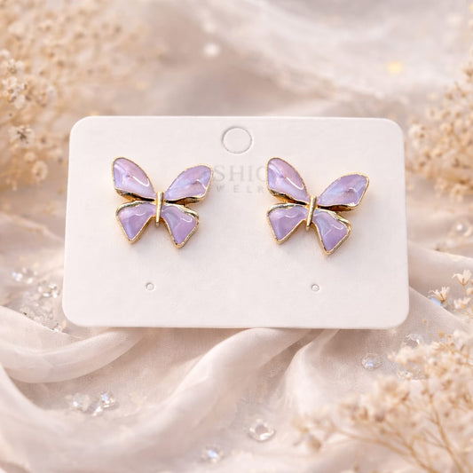 Butterfly-shaped earrings on a white card with a soft, blurred background